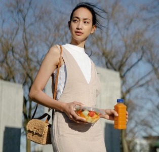 Девушка держит в руках бутылку со смузи и ланч-бокс с фруктами