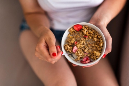 Женщина ест гранолу с ягодами